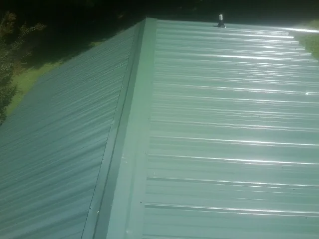 New green metal panels meeting at the ridge of a roof — Flat Roof Repair work by our crew in Shannon